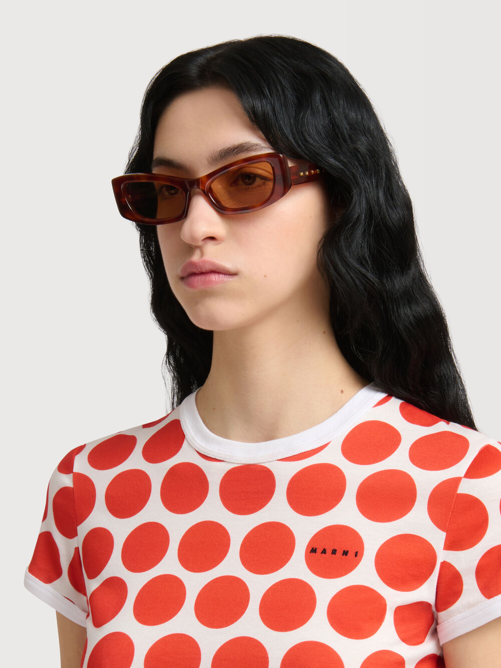 Model wearing amber Marni sunglasses and a red polka dot T-shirt.