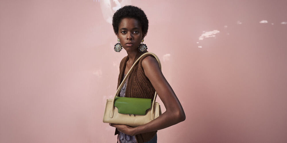 Model carrying a beige Marni Trunkette bag with contrasting green flap
