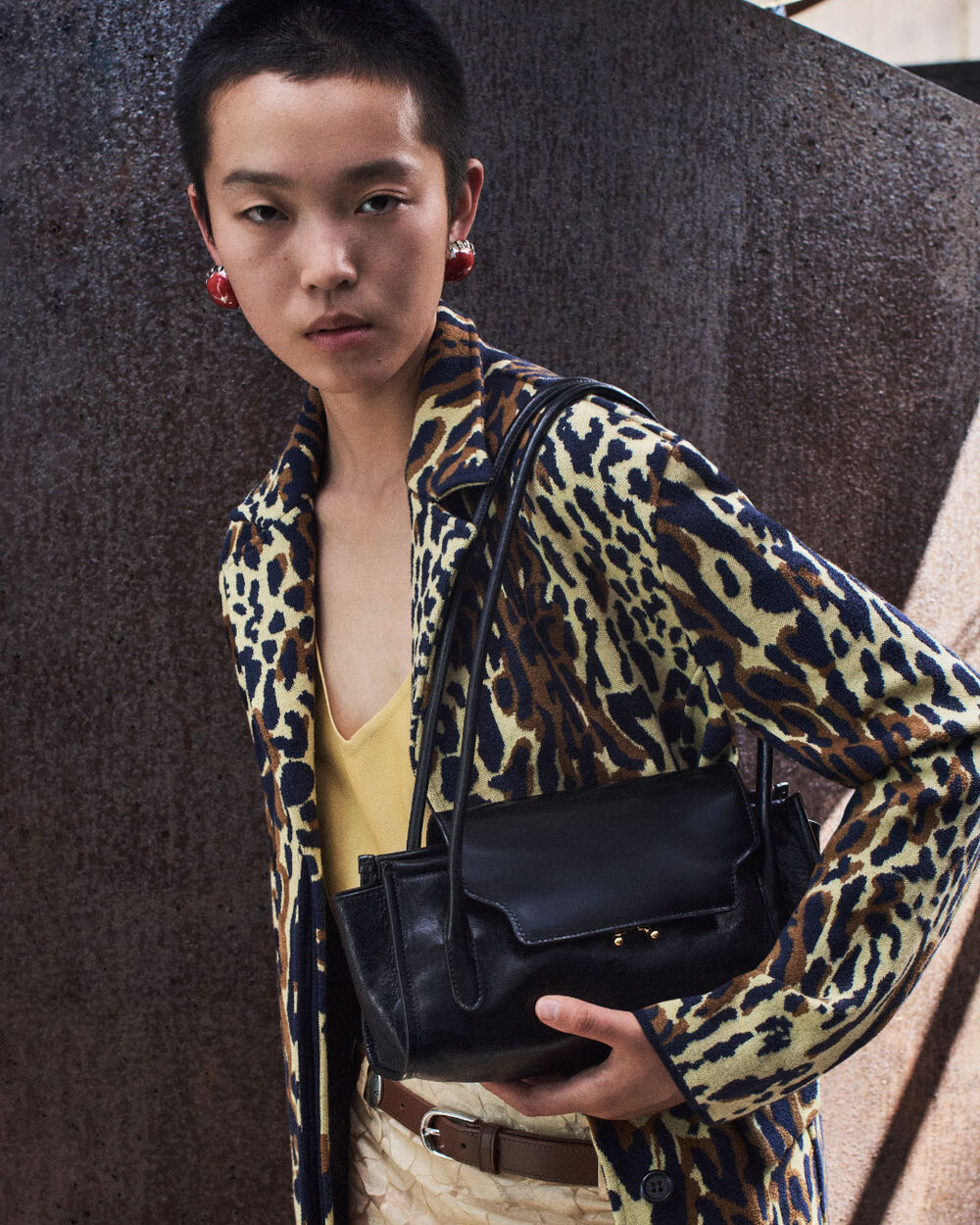 Model carrying a black Marni Trunkette bag, styled with an animal-print jacket