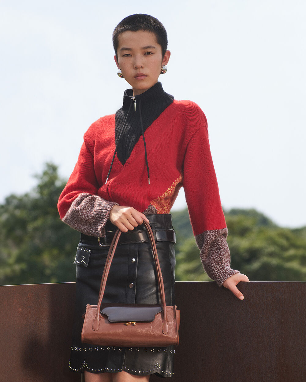 Model wearing a red Marni knit top and carrying a brown Trunkette bag