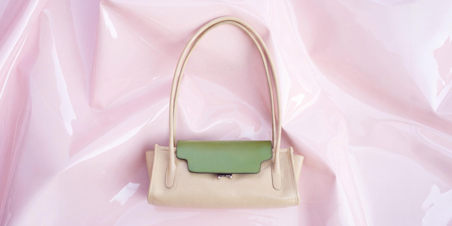 Cream Marni Trunkette bag with contrasting green flap and long tubular handles on a pale pink glossy background