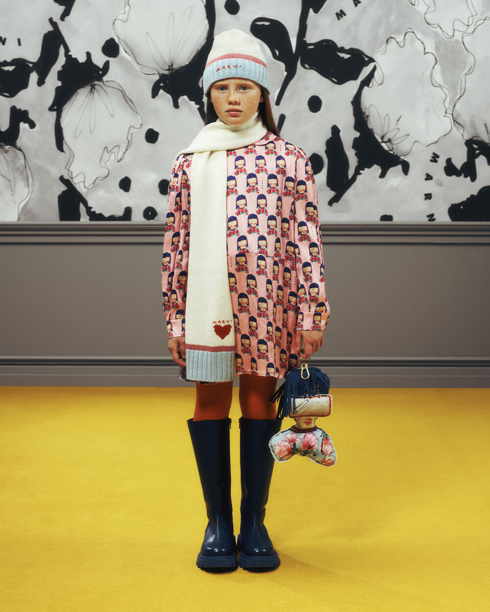Child wearing a Marni Kids printed dress with a knitted beanie and long scarf