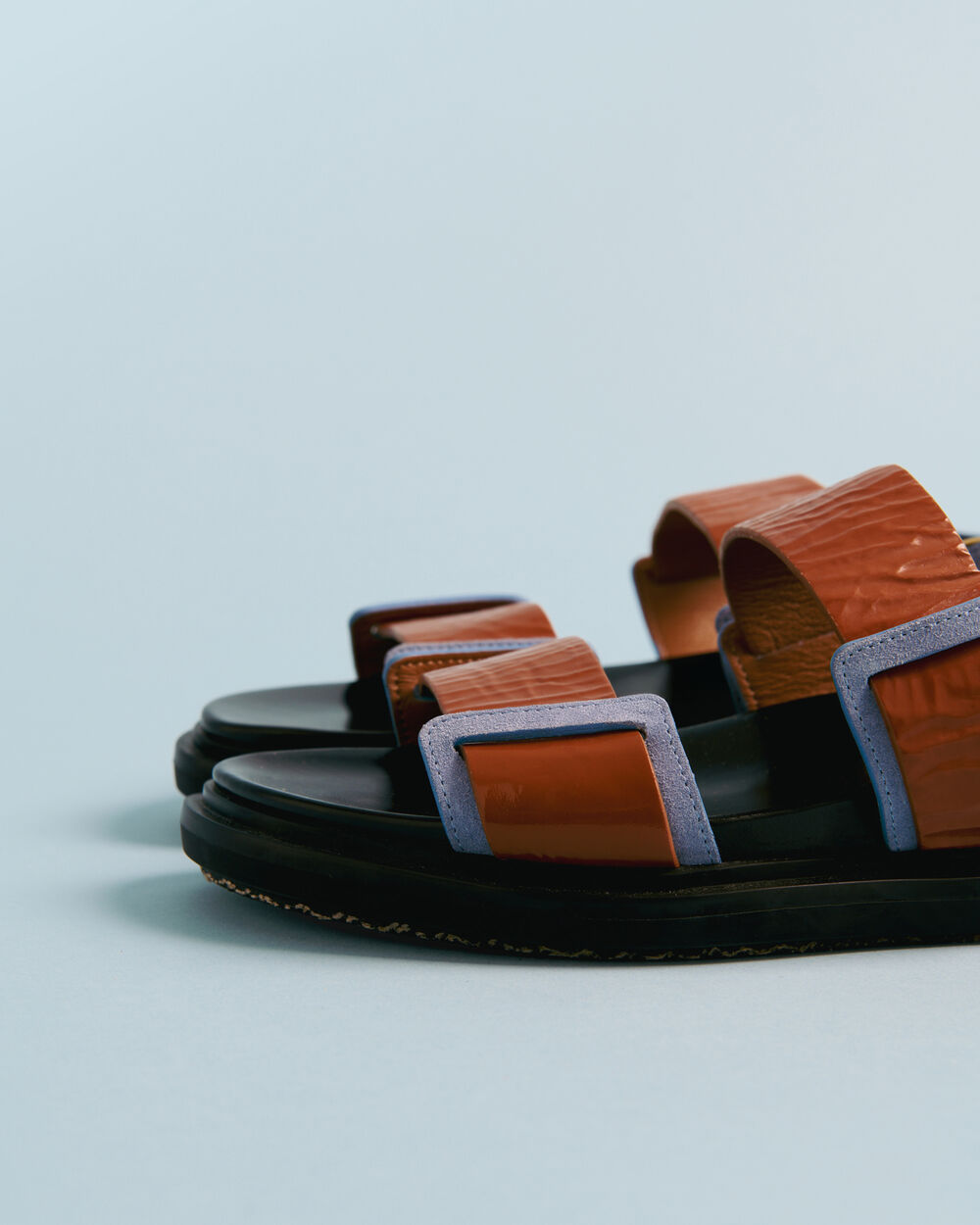 Brown Marni leather sandals set on a light blue background